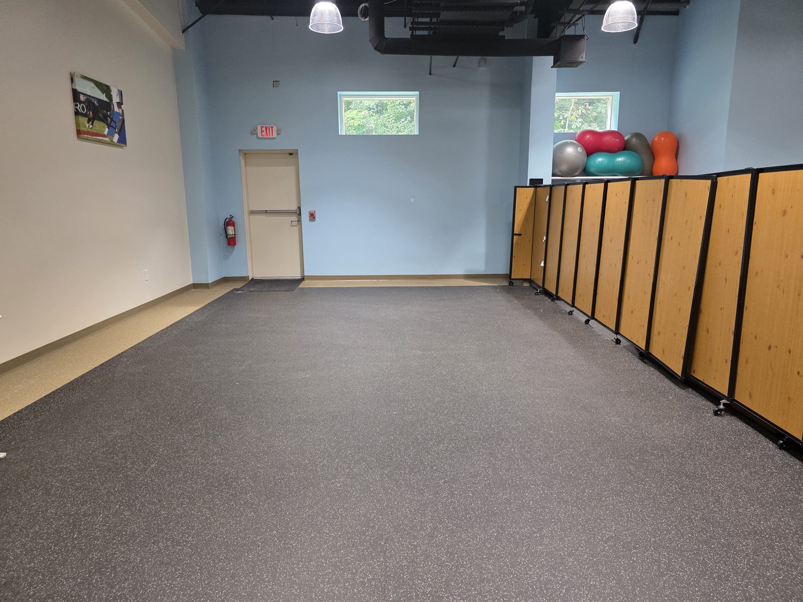 Empty open training floor with rubber flooring, movable wood partitions and exercise balls